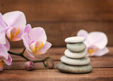 Fototapeta Storczyk - Spa stones and a pink Orchid on a brown wooden background