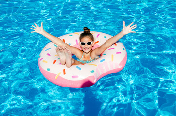 Cute smiling little girl in swimming pool with rubber ring