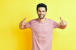 © GVS - Happy handsome man showing thumbs up sign on yellow background.