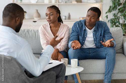 Marriage Crisis. Upset Black Couple Sitting At Counselor\'s Office, Ignoring Each Other