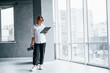 © standret - Woman in formal clothes and with camera in hand standing inside of empty room