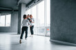 © standret - Woman in formal clothes and with camera in hand standing inside of empty room with man and little boy that running and having fun