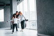 © standret - Woman in formal clothes and with camera in hand standing inside of empty room with man and little boy that running and having fun