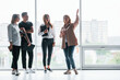 © standret - Woman holding her professional camera. Group of business people in formal clothes standing indoors near big window