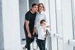© standret - Woman in formal clothes and with camera in hand standing inside of empty room with man and little boy