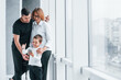 © standret - Woman in formal clothes and with camera in hand standing inside of empty room with man and little boy