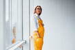© standret - Female worker or engineer in yellow uniform and hard hat standing indoors