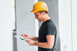 © standret - Male worker or engineer in yellow hard hat standing indoors with notepad