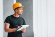 © standret - Male worker or engineer in yellow hard hat standing indoors with notepad