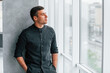 © standret - Elegant man in black shirt leaning on the wall indoors and looking through the big window