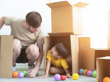 Young Boy Is Playing Hide And Seek With His Dad Inside A Cardboard Box In His Room