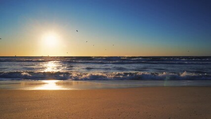 Wall Mural - Tropical sunrise on the beach. Summer morning. Waves splashing onto the sand.