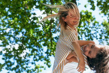 Smiling loving mother and her cute little girl playing in the park during the picnic. Happy pretty woman and smiling daughter spending time together on a sunny day. Cheerful mom and kid have fun.