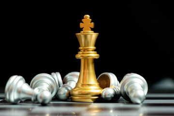 Wall Mural - Gold king chess piece win over lying down pawn on black background (Concept for leadership, crisis management)