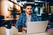 © BullRun - Portrait of serious hipster guy making research for exam preparation using netbook and wifi in college, young man looking at camera disappointed with problem using laptop computer in coworking space.