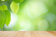 Empty wooden table on green nature background with beauty bokeh under sunlight. Counter bar for product display.