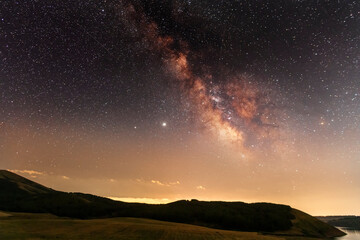 Wall Mural - beautiful night landscape, starry sky with bright milky way galaxy above the mountains with green fi
