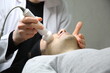 © Erkan - Professional beautician is rejuvenating male face by cavitation laser apparatus. Man is lying on massage table and relaxing