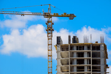 A high-rise building under construction with a yellow construction crane against a blue sky