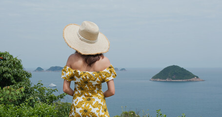 Poster - Woman wear straw hat and look at the sea view in countryside