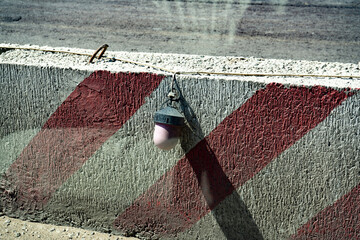 A concrete block of a fence with a white and red paint and a signaling red lantern.