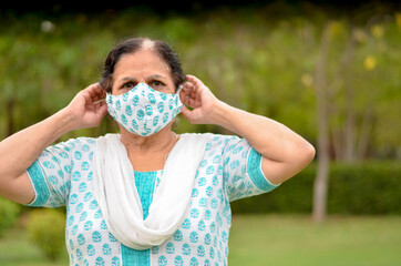 Close up Portrait of a senior Indian lady and young lady wearing surgical cotton mask matching with her salwar kameez to protect herself from Corona Virus (COVID-19) pandemic, getting ready in India