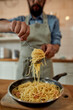 © Svitlana - Cropped shot of man in apron, cook holding spaghetti on fork while preparing garlic butter shrimp pasta at home. Mediterranean cuisine concept