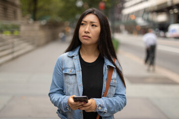 Wall Mural - Young Asian woman walking street texting cellphone