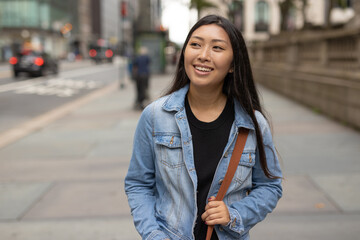 Wall Mural - Young Asian woman walking city street smiling happy