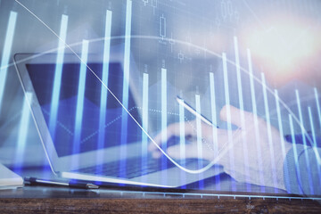  Double exposure of man's hands holding and using a digital device and forex graph drawing. Financial market concept.