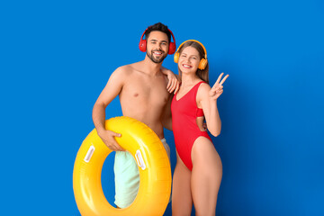 Sticker - Young couple with headphones and inflatable ring on color background