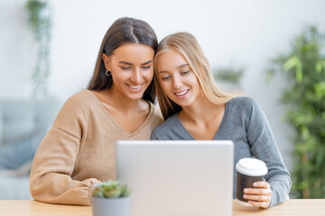 two happy young women using laptop