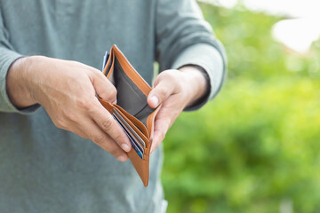 Wall Mural - Man holding empty wallet. Money problem concept. Outdoor shooting with green blur background