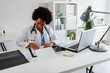© lordn - Woman doctor with stethoscope looking at medical papers at her office working hard