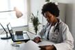 © lordn - Woman doctor with stethoscope looking at medical papers at her office working hard