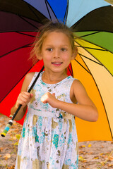 Wall Mural - little girl under umbrella. LITTLE BEAUTIFUL GIRL UNDER A BRIGHT COLORED UMBRELLA. CHILD SMILES AND SHOWS HIMSELF
