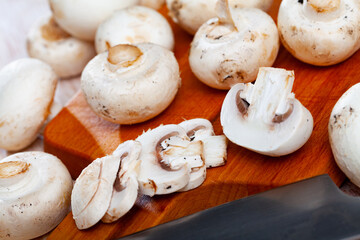 Fresh champignon mushrooms on a wooden cutting board. High quality photo