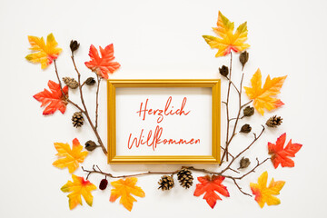 Wall Mural - Golden Frame With German Text Herzlich Willkommen Means Welcome. Beautiful, Colorful Autumn Leaf Decoration With Maple Leaf And Fir Cone. White Background