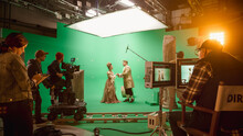 On Set: Famous Female Director Controls Cameraman Shooting Green Screen Scene With Two Actors Talented Wearing Renaissance Clothes Talking. Crew Shooting Period Costume Drama Movie.