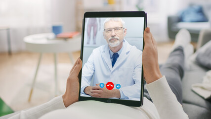 Wall Mural - Young Girl at Home Using Digital Tablet to Talk to Her Doctor via Video Conference Medical App. Woman Checks Possible Symptoms with Professional Physician, Using Online Video Chat Application