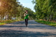 © Serhii - young white fitness woman runs on country road, front view.