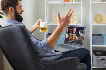 Wall Mural - Virtual party with friends online. A man with a glass of beer celebrates his birthday with a group of friends at home remotely.