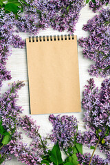 Poster - Open blank notepad with  lilac flowers on wooden table.