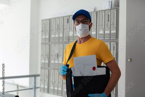 Mailman delivering mail with mail-bag and protective mask and gloves during virus pandemic.