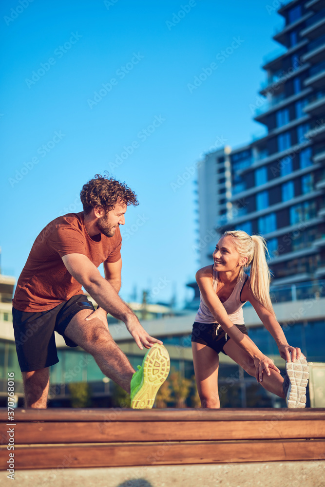 Young adult sporty couple working out outdoors. - obrazy, fototapety, plakaty 