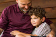 © digitalskillet1 - Hispanic father sitting and hugging his son.