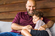 © digitalskillet1 - Hispanic father sitting and hugging his son.