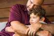 © digitalskillet1 - Hispanic father sitting and hugging his son.