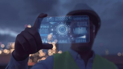 Male Industrial Engineer Works with glasses shows a conceptual hologram Industrial Hud display data on blurred background of large industry 