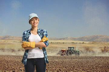 Poster - Female farmer posing on a rural field where a tractor is plugging